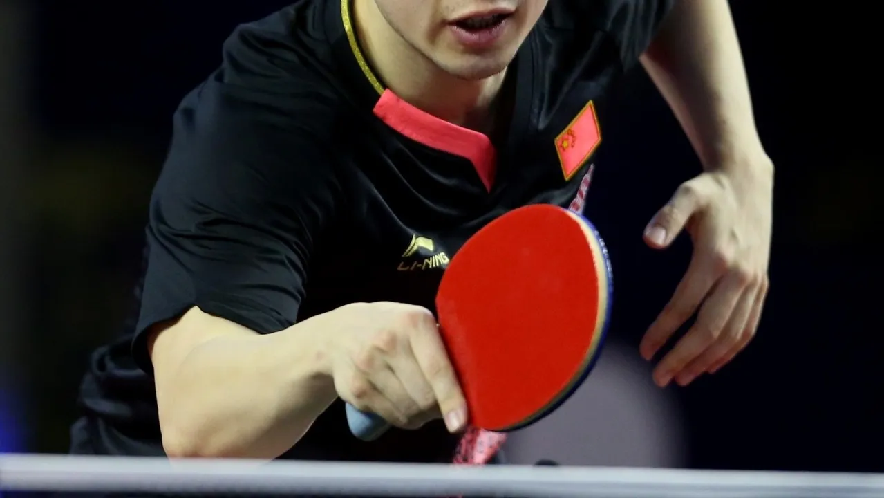 Table tennis player demonstrating the shakehand grip with thumb and index finger on either side of the blade